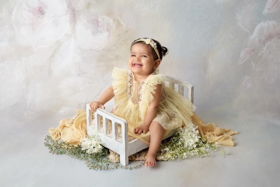 Bébé fille sur lit en bois blanc avec fleurs